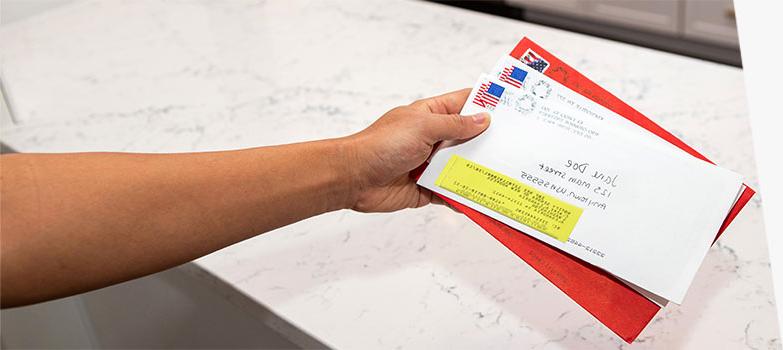 Person holding stack of forwarded 美国邮政总局 mail.